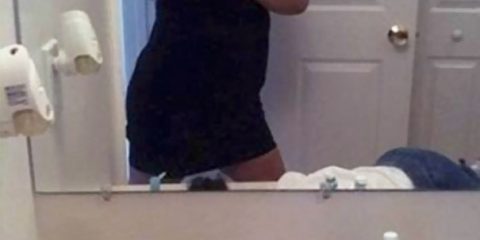 This mom is letting her toddler get a drink out of the sink by himself while she takes a selfie.